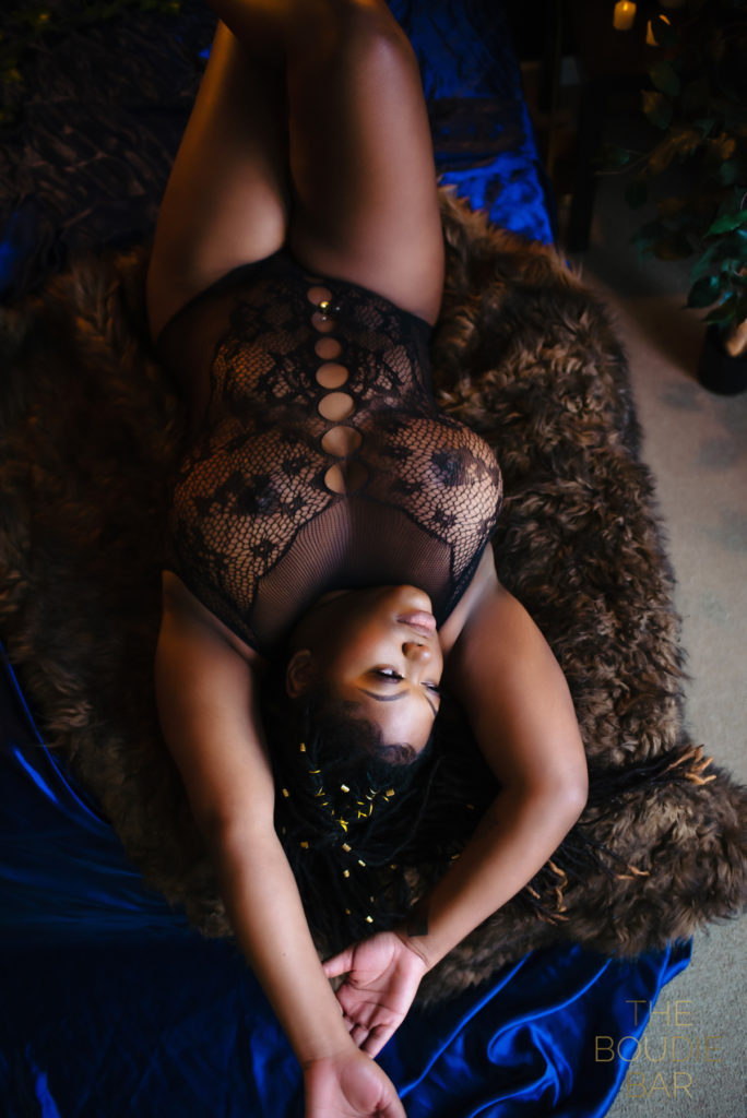 boudoir photo of a black woman laying on a bed in sexy lingerie