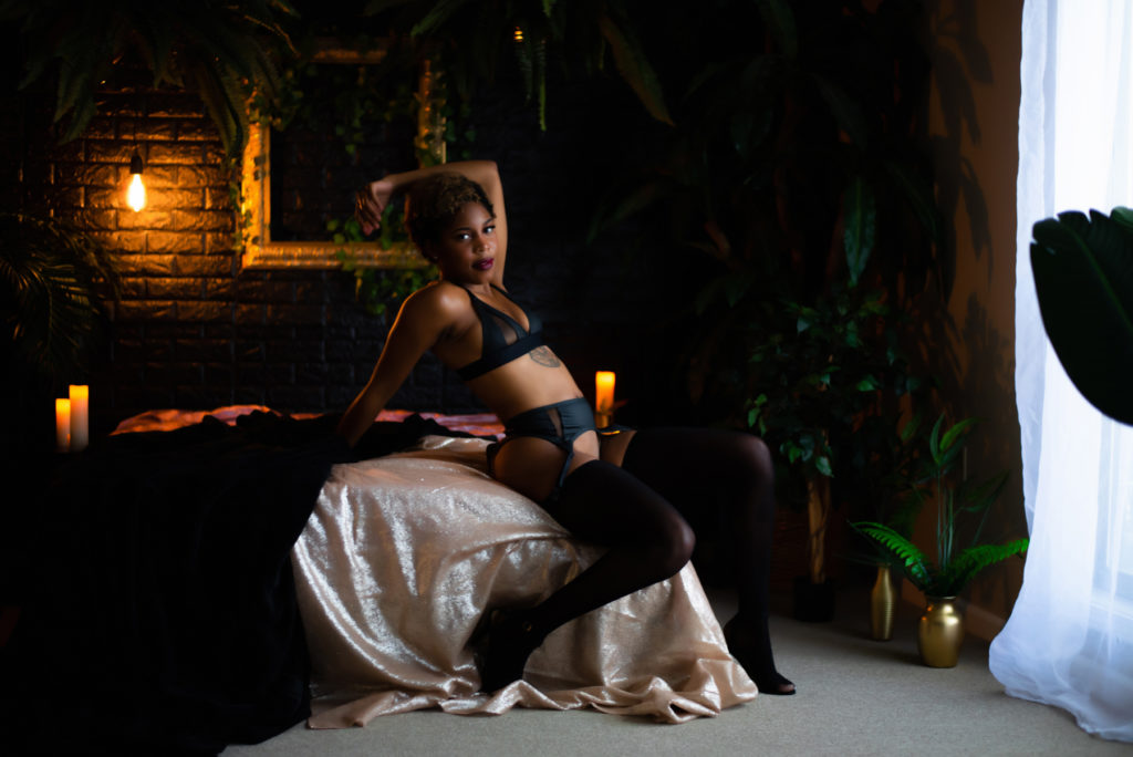 dark and moody boudoir photo with a woman sitting on a bed