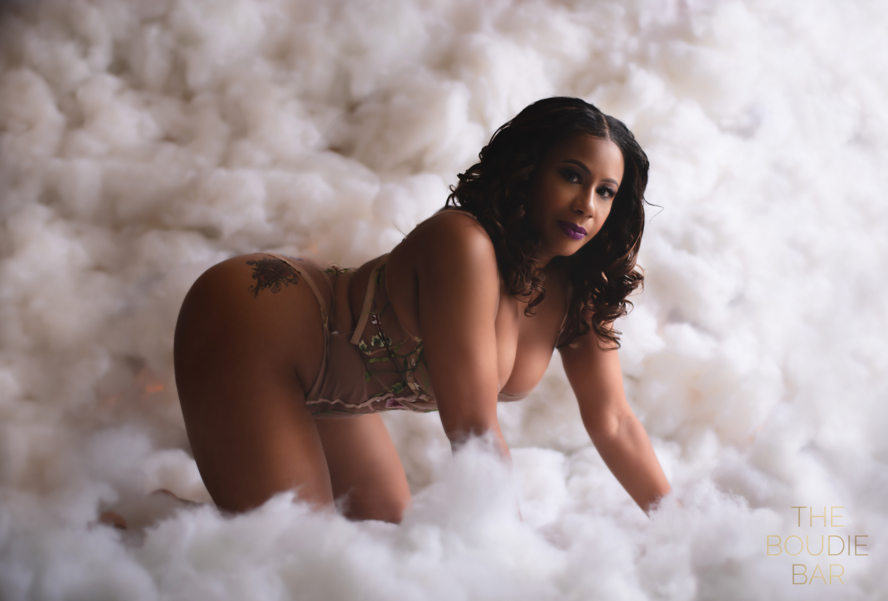 a boudoir image of a black woman crawling in the clouds