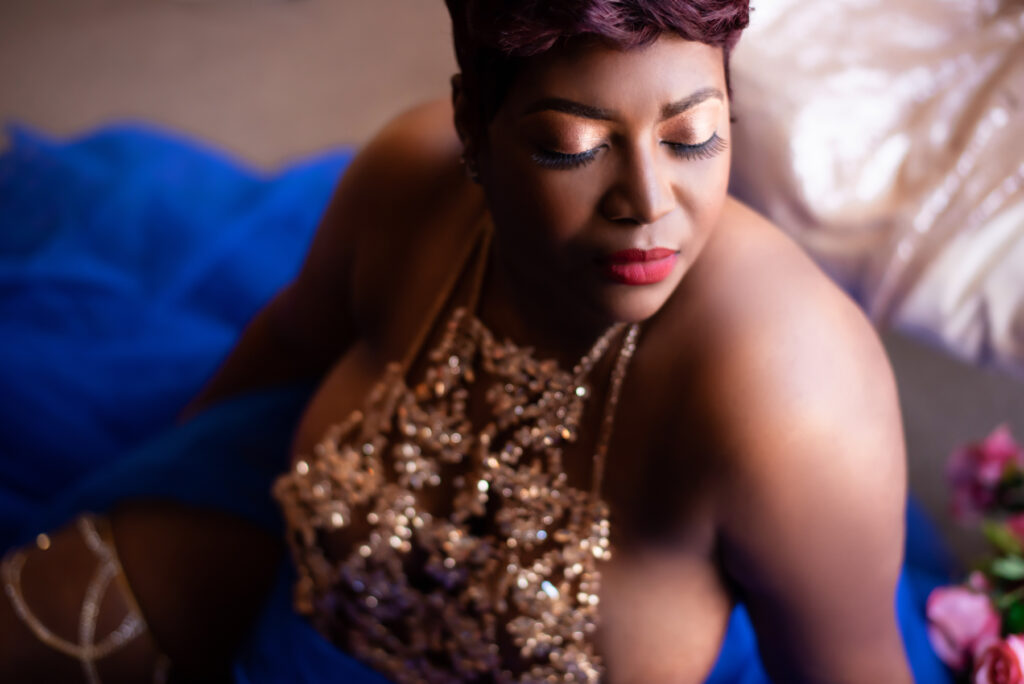 boudoir image of a black woman sitting on the floor wearing gold body jewelry.
