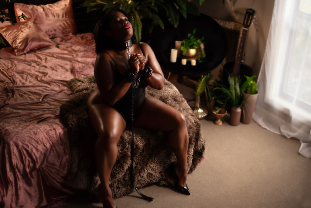 A boudoir image showing a black woman in kinky handcuffs.