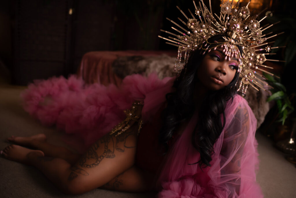 Atlanta boudoir photo with a beautiful black woman in a gold grown and pink robe.
