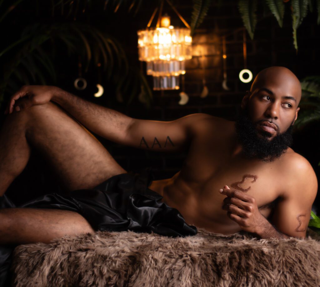 Atlanta boudoir photo showing a black man laying on a bed.