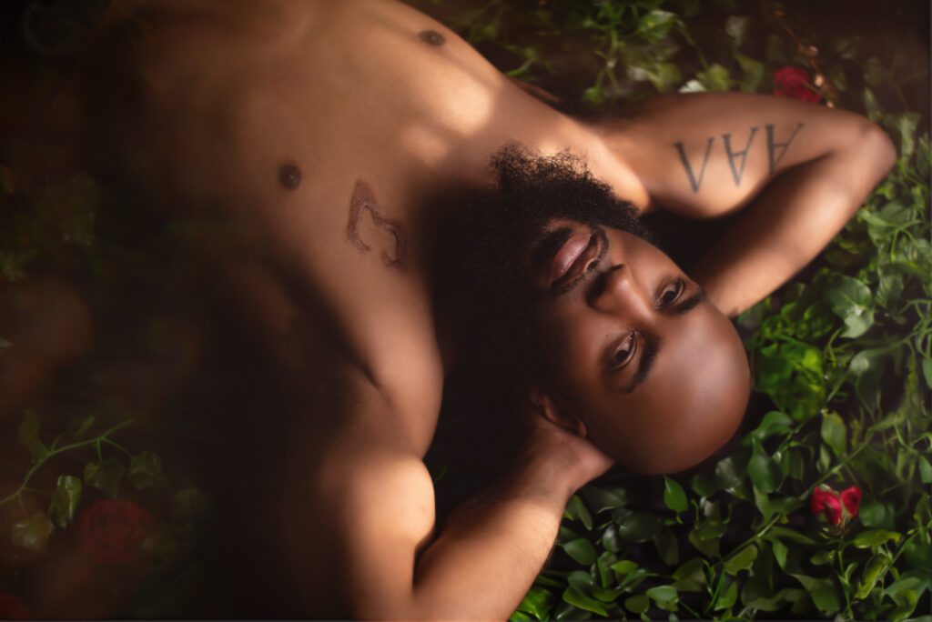 Atlanta boudoir photo of a black men laying in flowers.