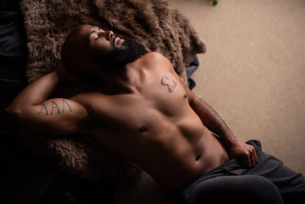 Atlanta boudoir photo featuring a black man in dark sweat pants.